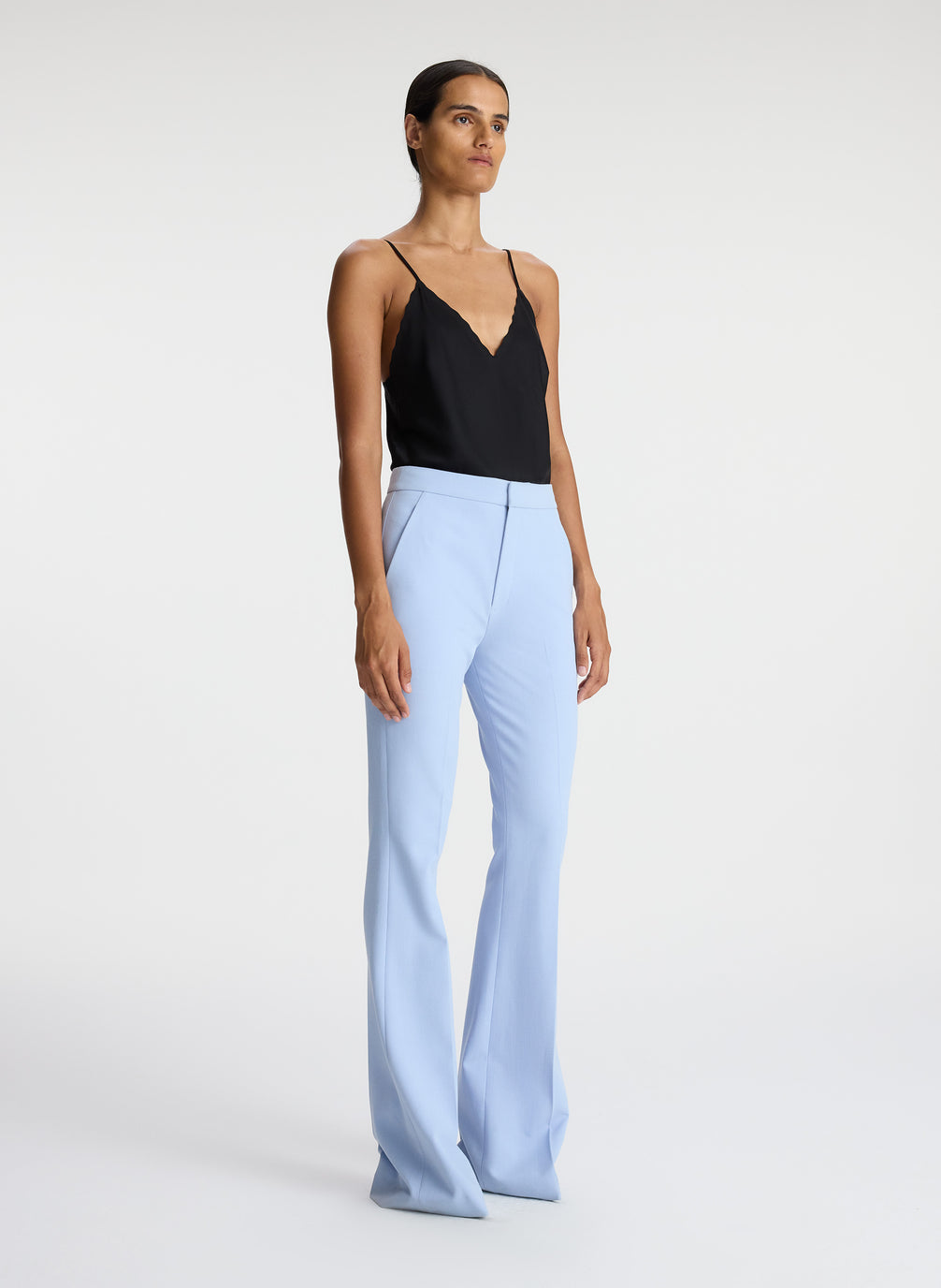 side view of woman wearing black satin camisole with light blue pants