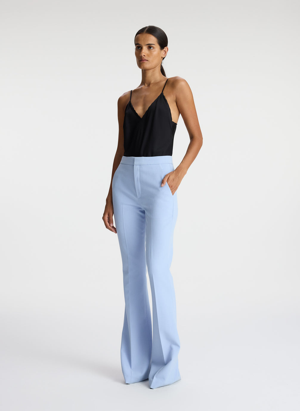 side view of woman wearing black satin camisole with light blue pants