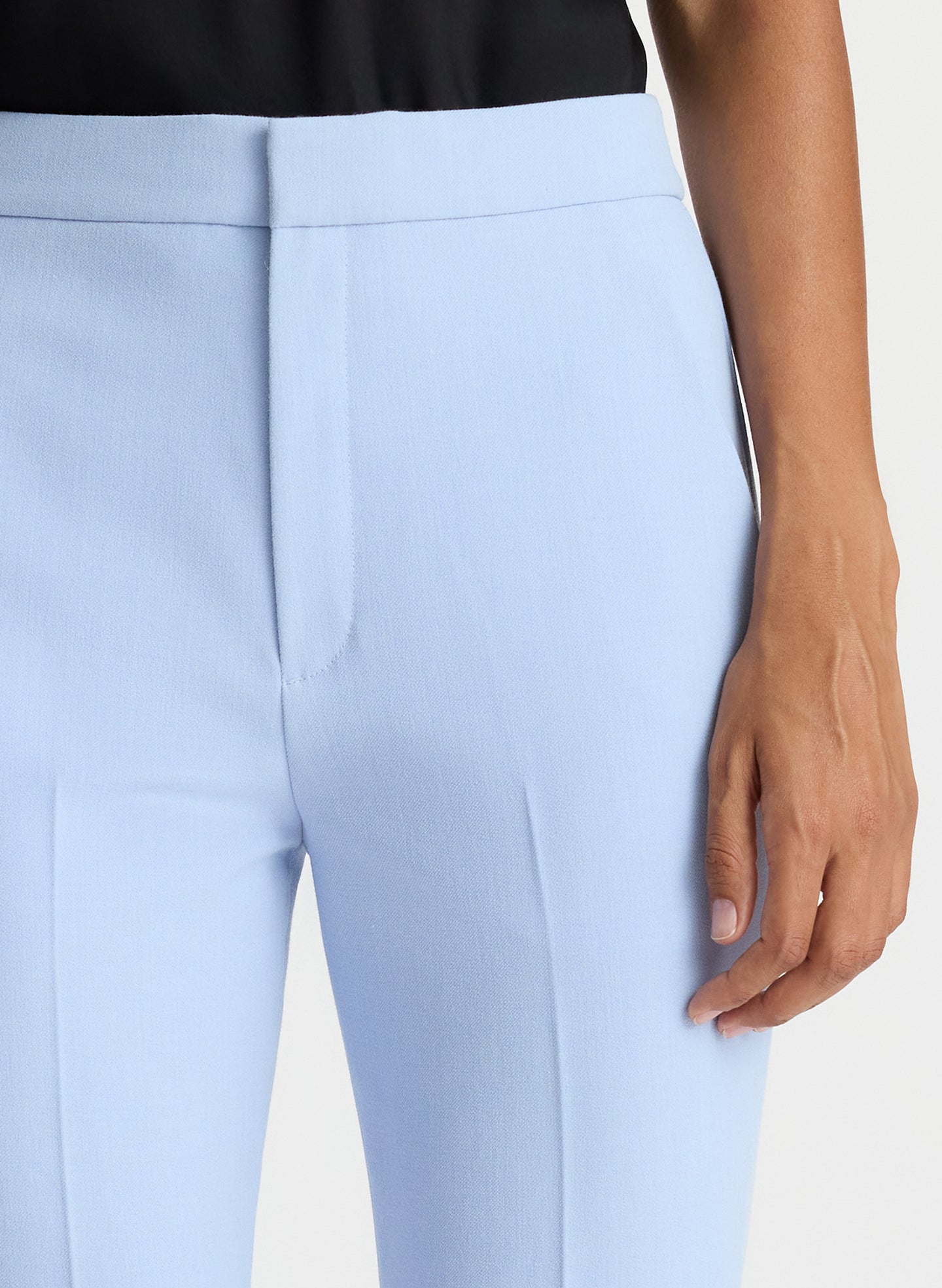 detail view of woman wearing black satin camisole with light blue pants