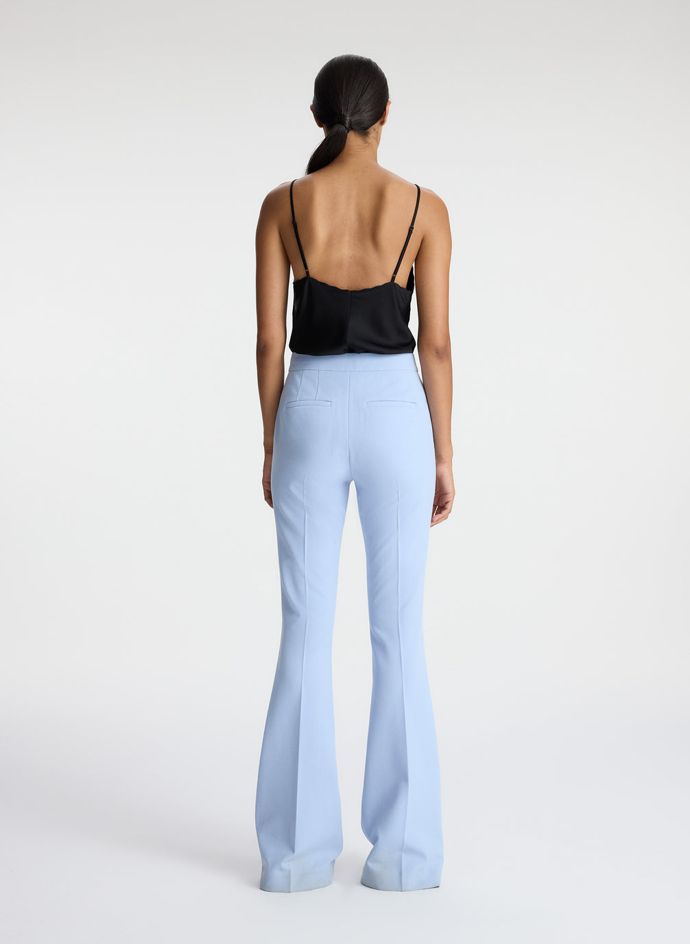 back view of woman wearing black satin camisole with light blue pants