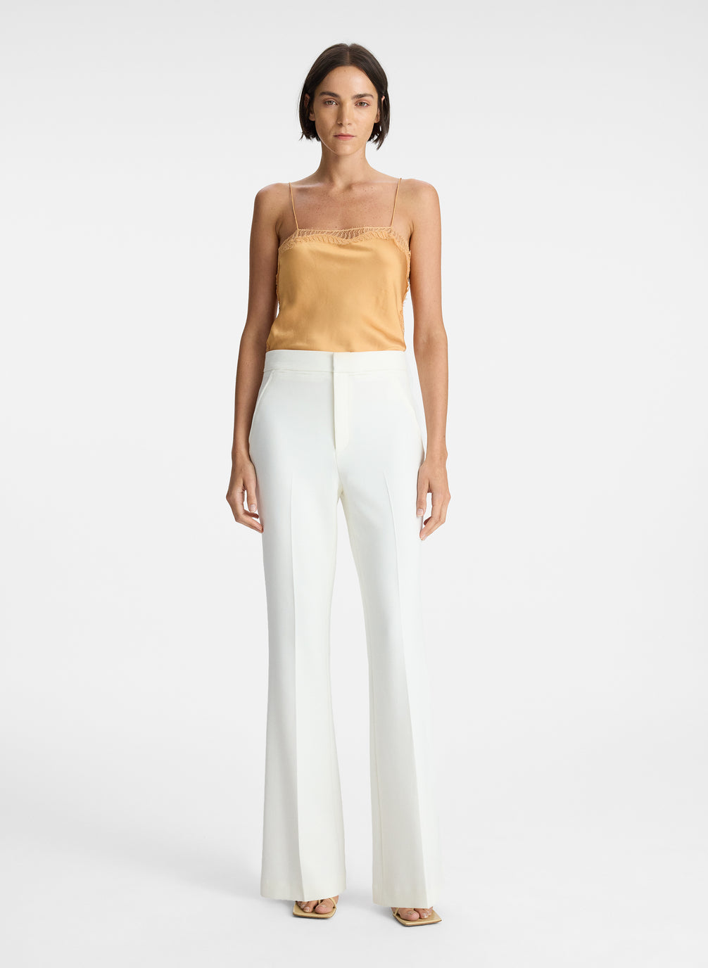 front view of woman wearing beige camisole and white pants