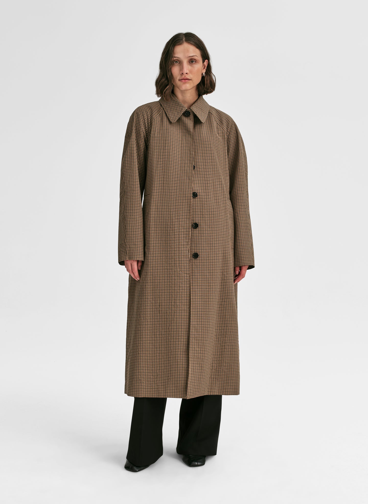 Woman wearing a long brown coat on a white background