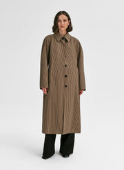 Woman wearing a long brown coat on a white background