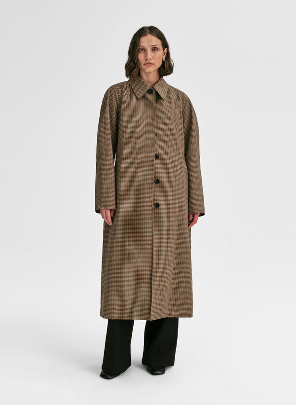 Woman wearing a long brown coat on a white background