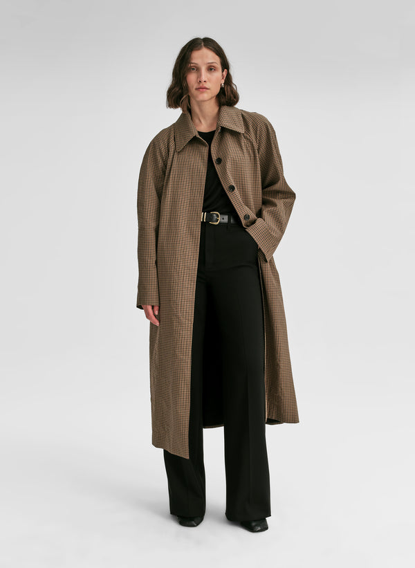 Woman wearing a long brown coat on a white background