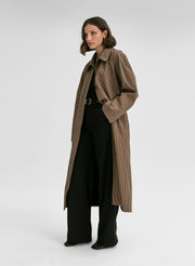 Woman wearing a long brown coat on a white background