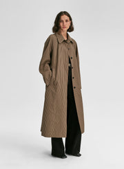 Woman wearing a long brown coat on a white background