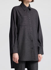 Person wearing a dark gray button-up shirt with a plain background