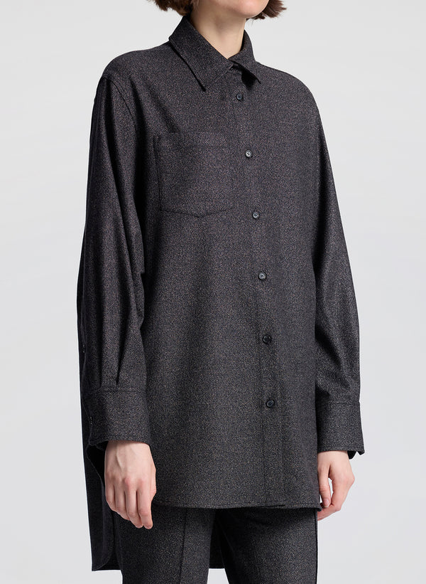 Person wearing a dark gray button-up shirt with a plain background