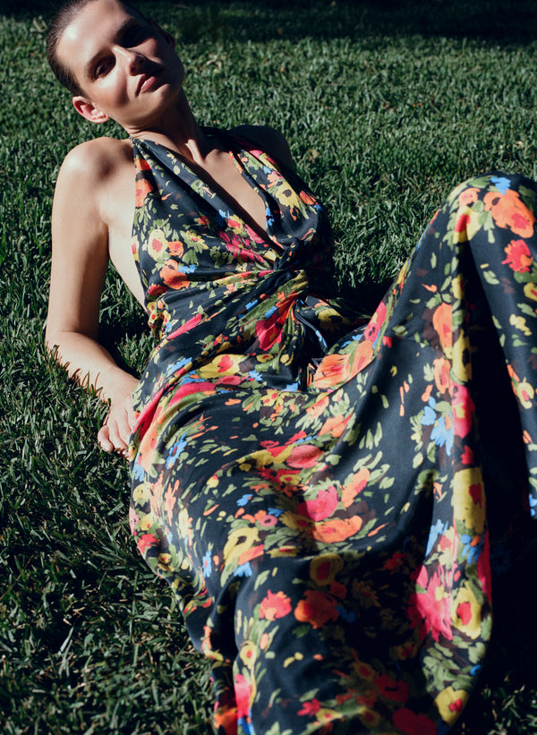 Woman in a colorful floral dress sitting on grass