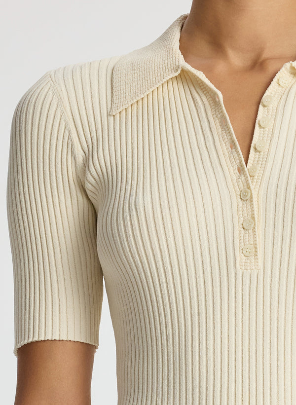 detail view of woman wearing cream short sleeve collared top and beige pants