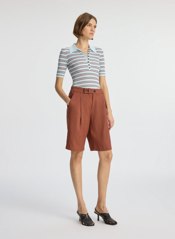 side view of woman wearing blue and brown striped shirt and brown shorts