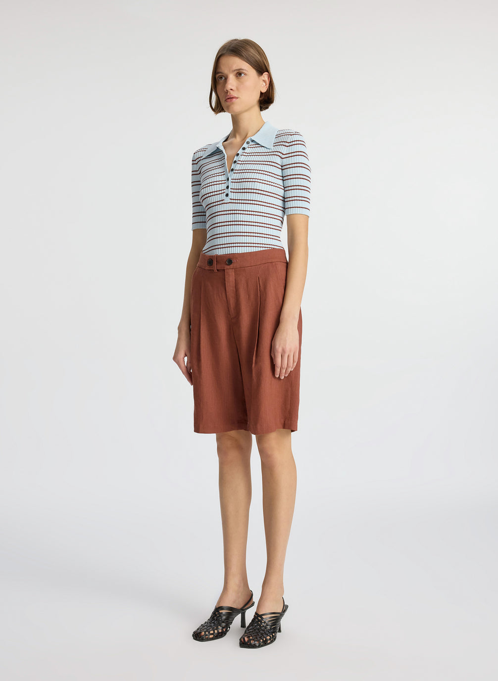 side view of woman wearing blue and brown striped shirt and brown shorts