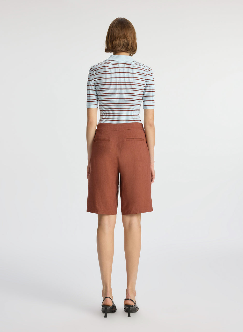 back view of woman wearing blue and brown striped shirt and brown shorts