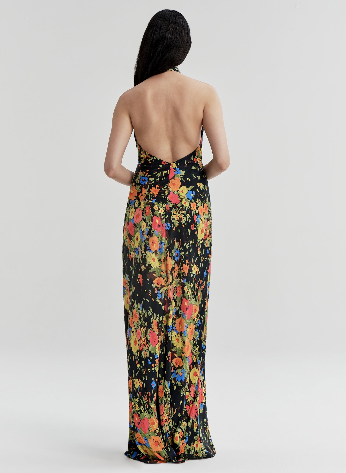 Woman wearing a floral gown with an open back on a white background