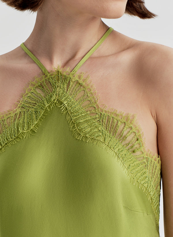 Woman wearing a green halter neck dress with lace details on a white background