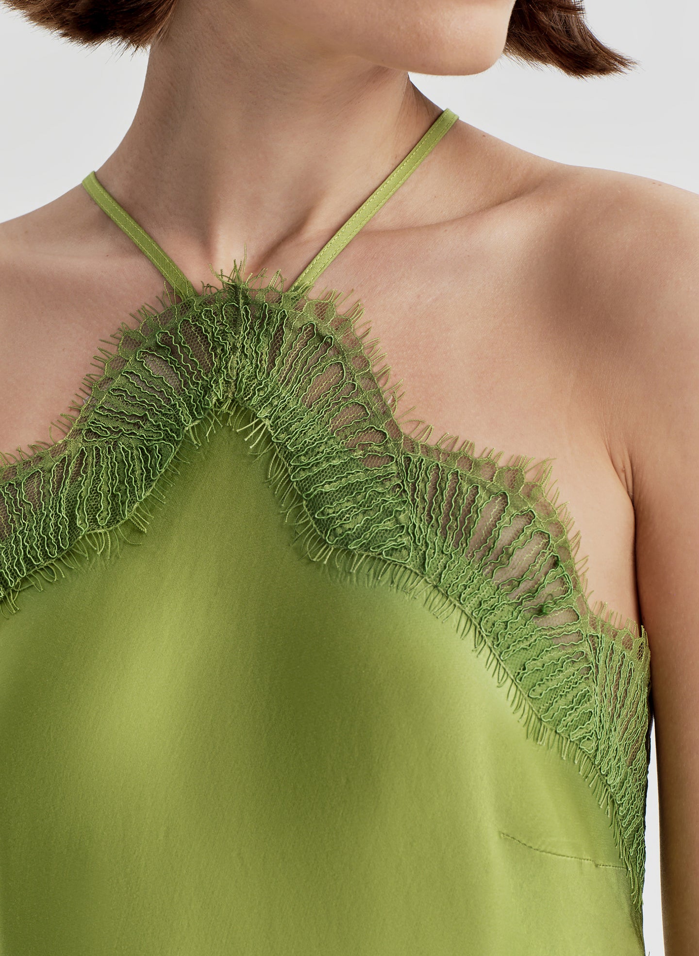 Green dress with lace detailing on a neutral background