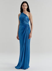 Woman wearing a blue pleated one-shoulder gown against a white background