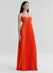 Woman wearing a bright orange halter neck gown on a white background