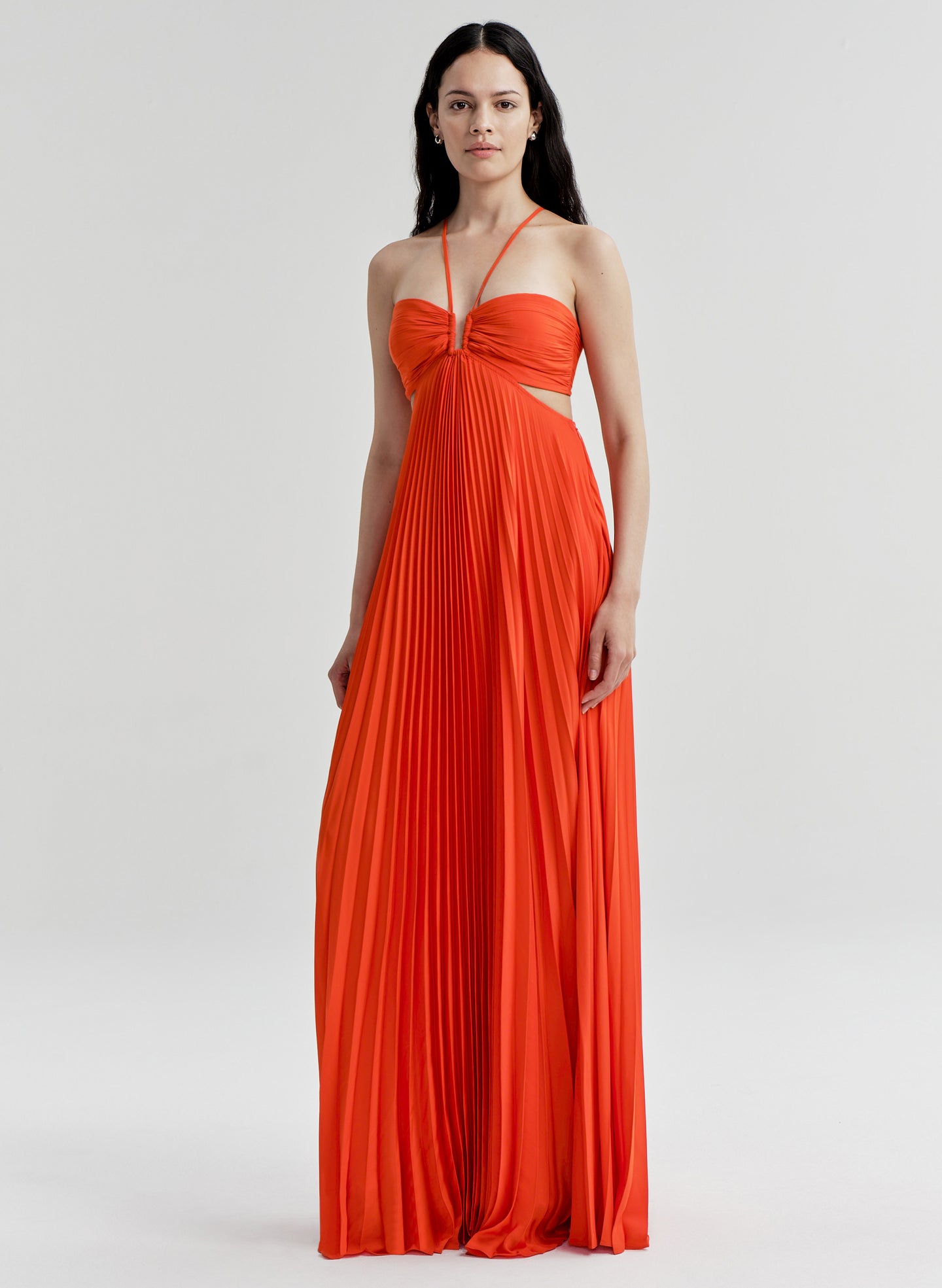 Woman wearing a bright orange halter neck gown on a white background