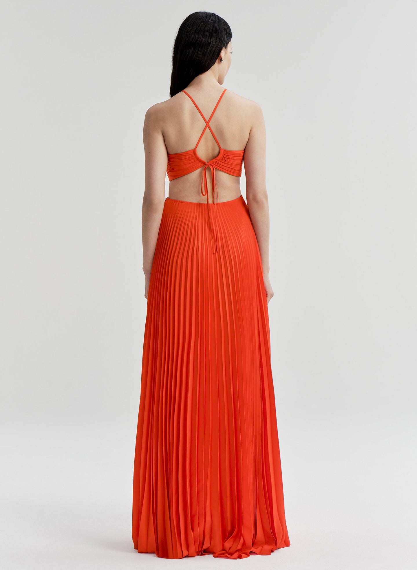 Woman wearing a bright orange halter neck gown on a white background