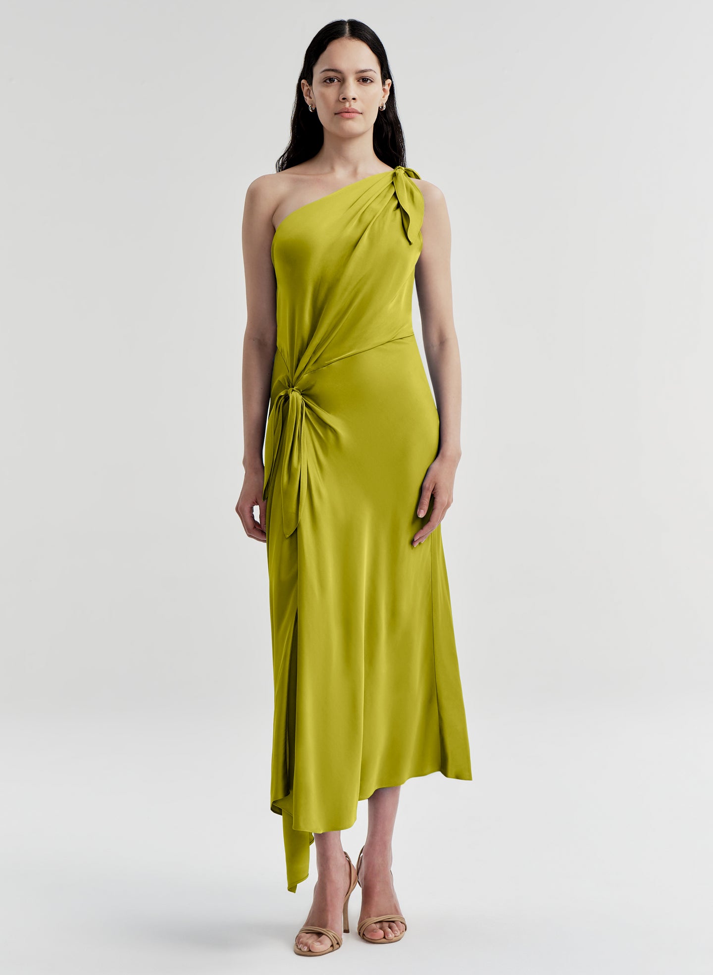 Woman wearing a green one-shoulder dress on a white background