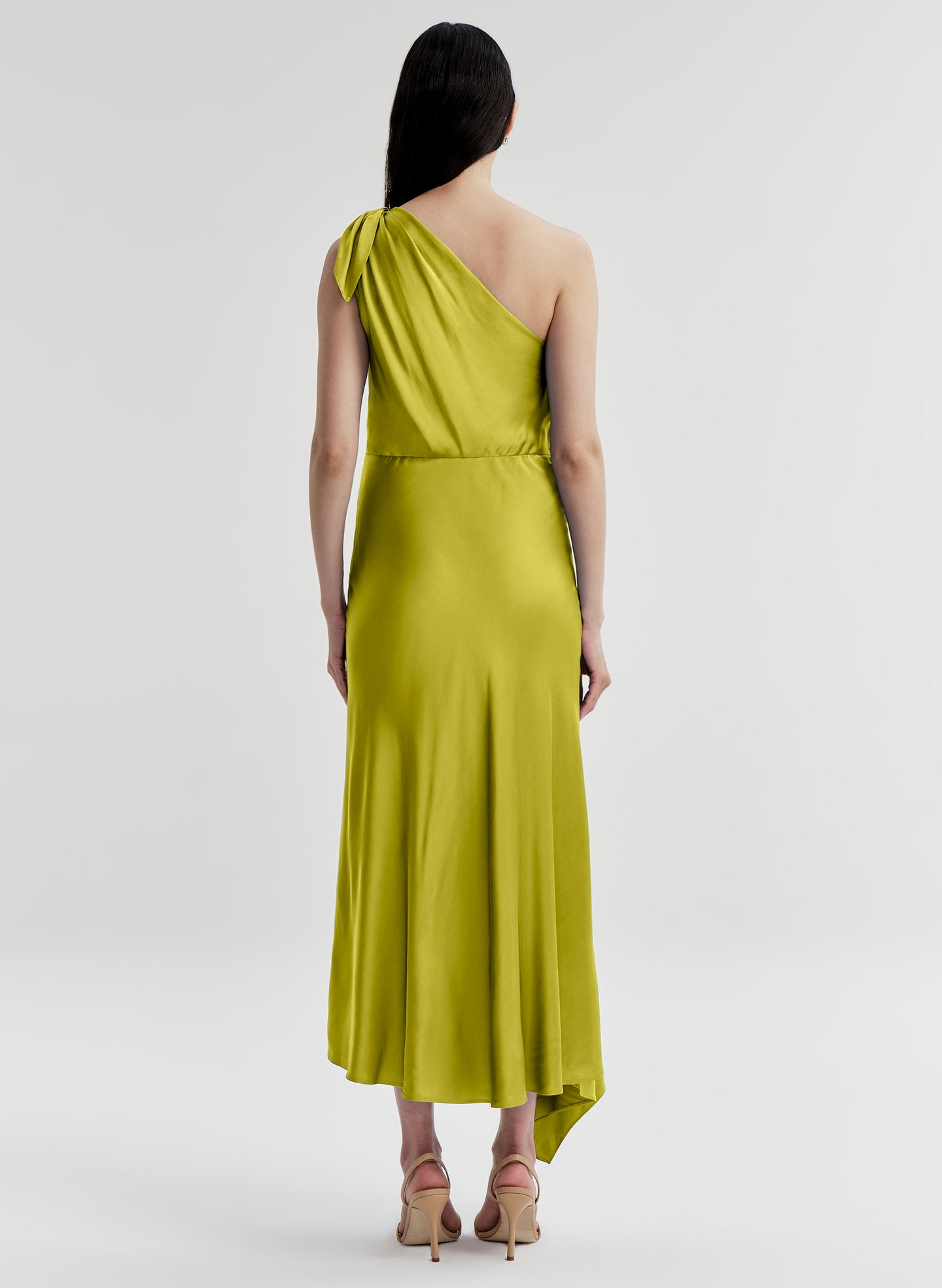 Woman wearing a green one-shoulder dress on a white background