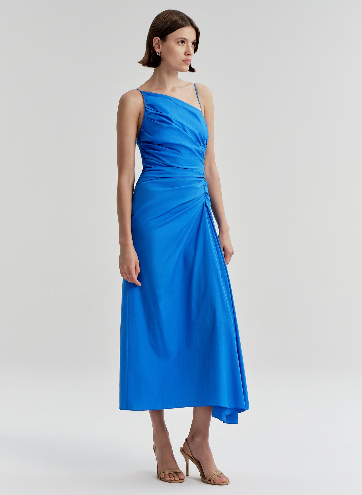 Woman wearing a blue midi dress on a light gray background