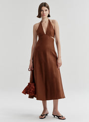 Woman wearing a brown halter neck dress on a white background