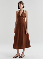 Woman wearing a brown halter neck dress on a white background
