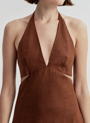 Woman wearing a brown halter dress with cut-out design on a white background