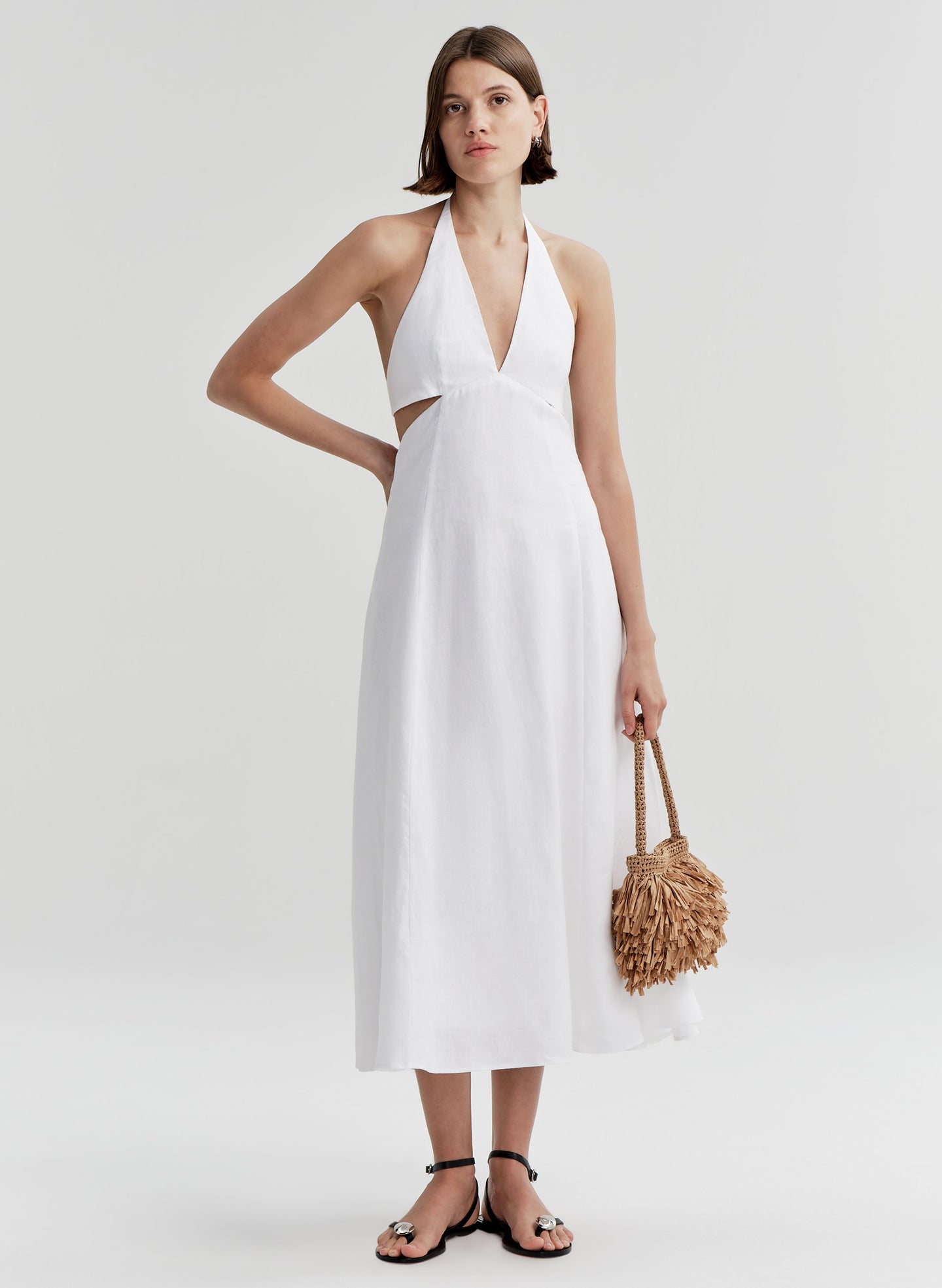 woman wearing white dress carrying tan raffia shoulder bag
