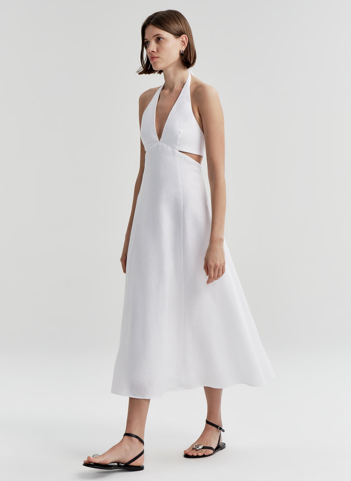 Woman wearing a white halter neck dress on a plain background