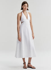 Woman wearing a white halter neck dress on a plain background