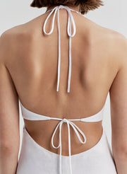 White halter neck dress with open back on a neutral background
