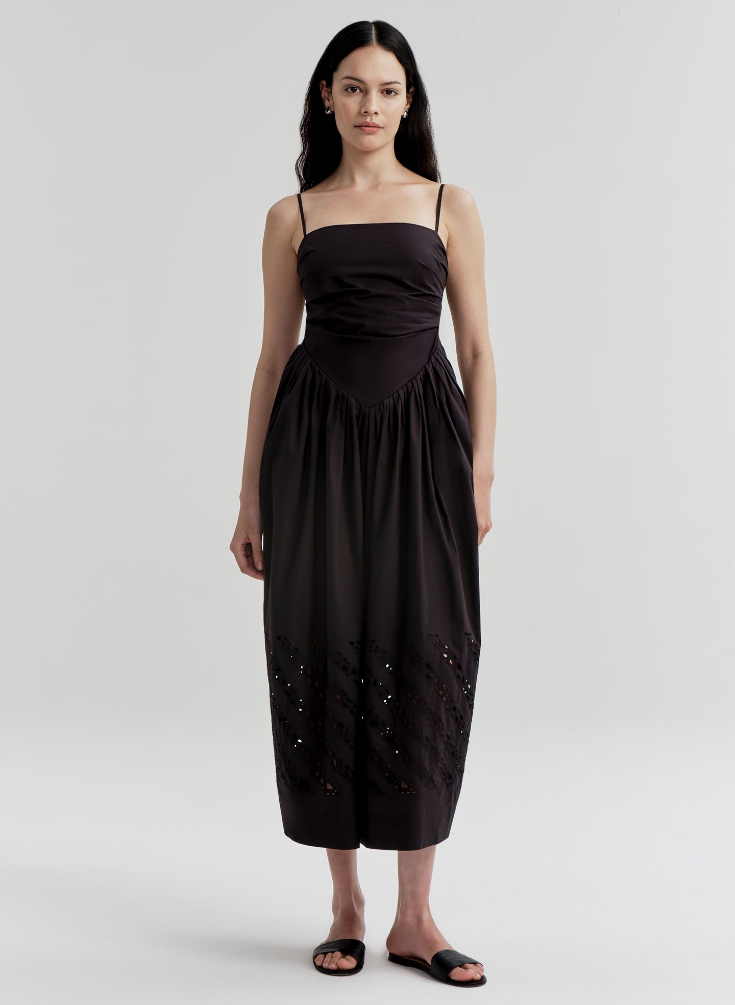 Woman wearing a black dress with cut-out details on a white background