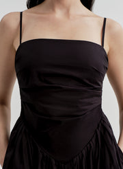 Woman wearing a black dress with thin straps on a plain background