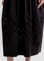 Woman wearing a black dress with cut-out details on a white background