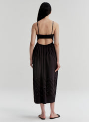 Woman wearing a black dress with cut-out details and an open back on a white background