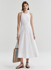 Woman wearing a white sleeveless dress on a plain background