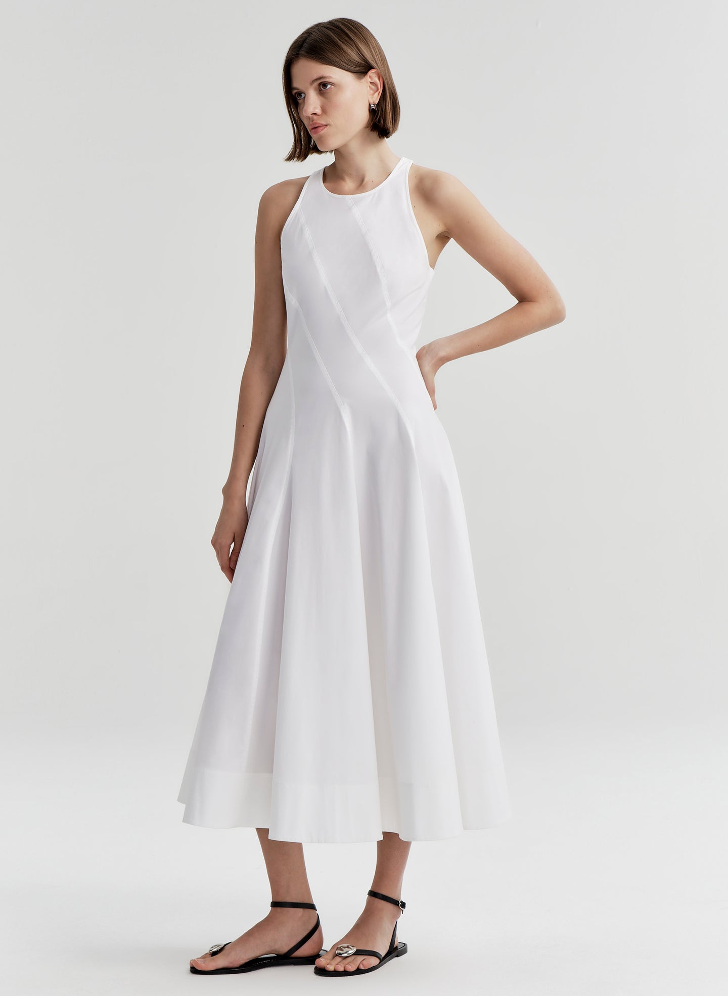 Woman wearing a white sleeveless dress on a plain background