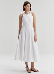 Woman wearing a white sleeveless dress on a plain background
