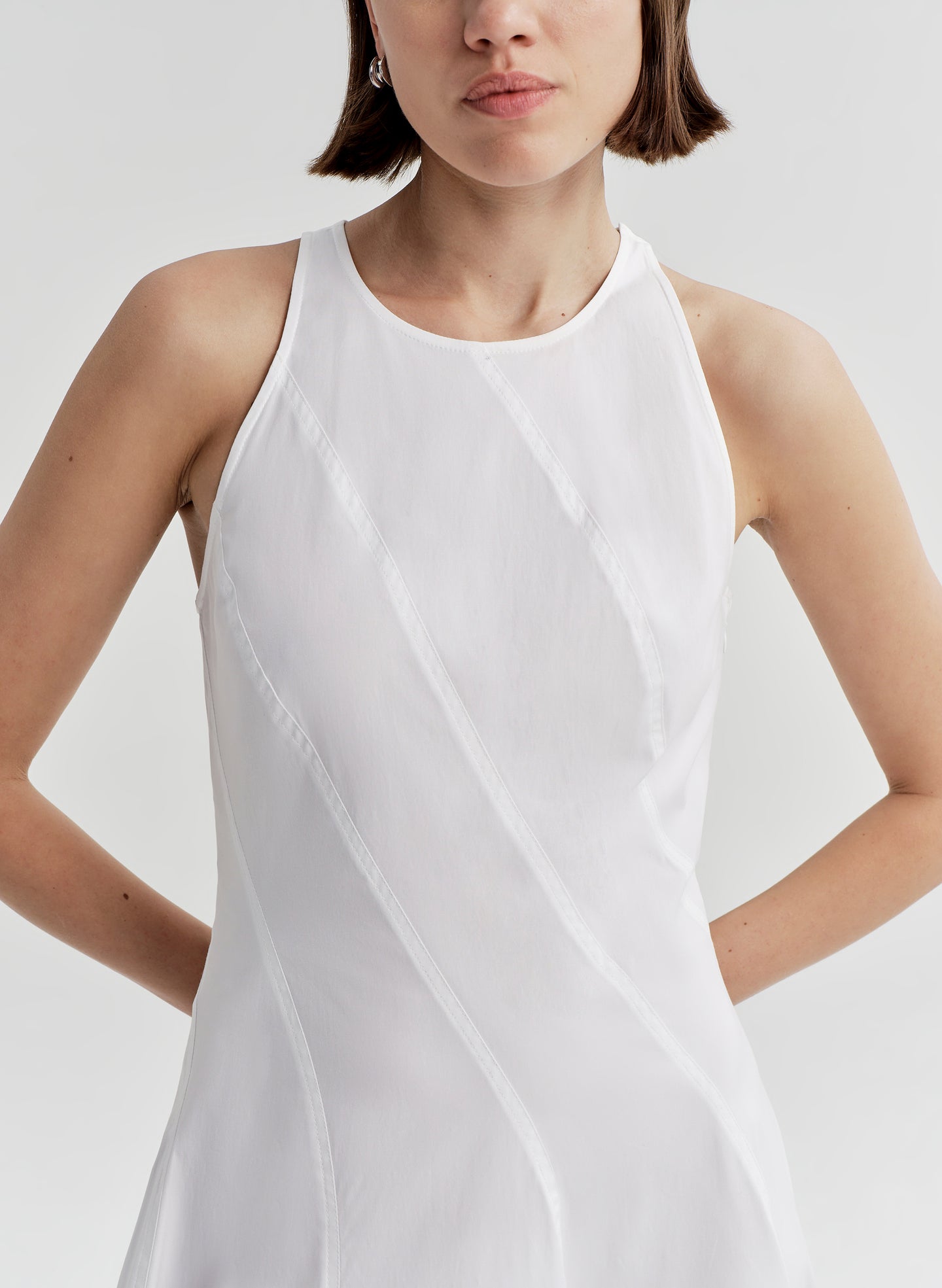 Woman wearing a white sleeveless dress on a plain background