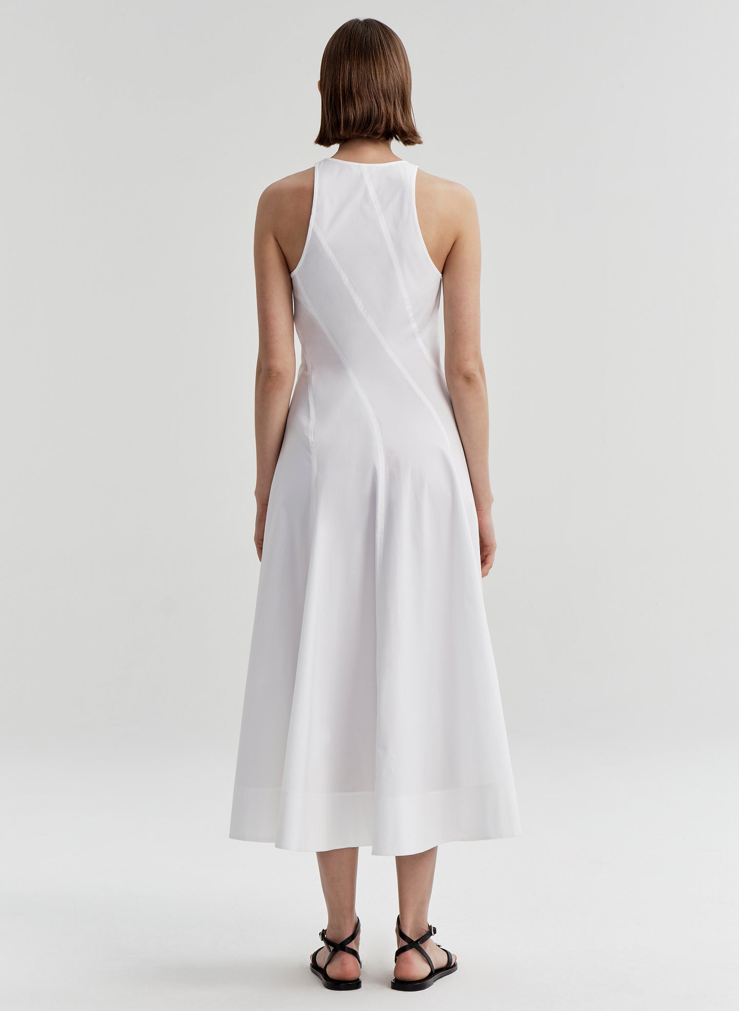Woman wearing a white sleeveless dress on a plain background