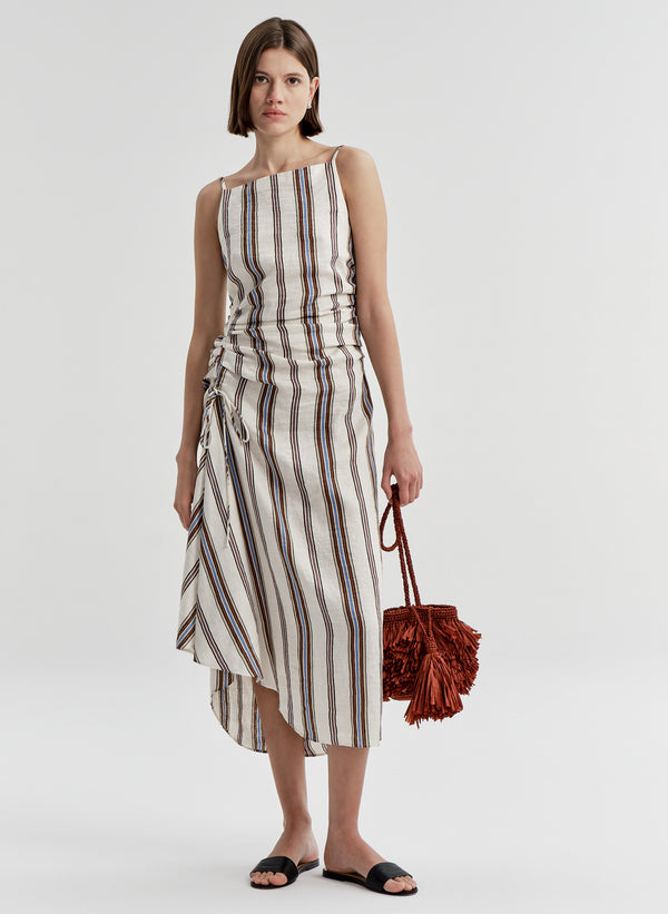 woman in stripe dress carrying brown raffia bag
