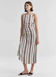 Woman wearing a sleeveless linen dress with brown and blue striped pattern on a white background