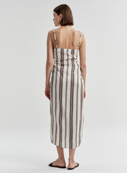 Woman wearing a sleeveless linen dress with brown and blue striped pattern on a white background