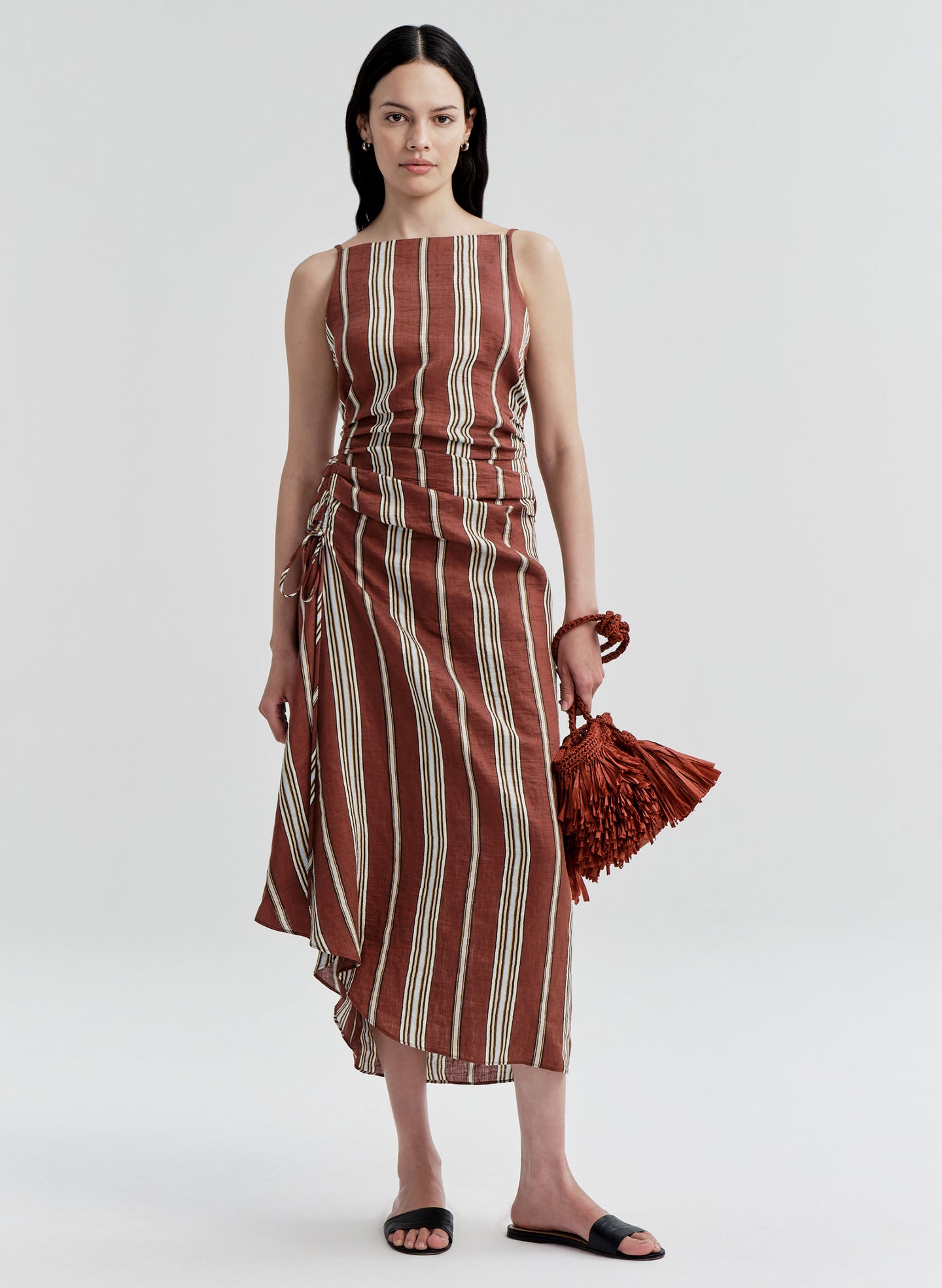 Woman wearing a linen brown and beige striped dress on a white background