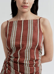 Woman wearing a linen brown and beige striped dress on a white background