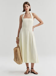 Woman wearing a beige halter neck dress on a plain background